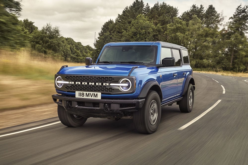 Vista frontale del nuovo Ford Bronco blu che percorre una zona di campagna.