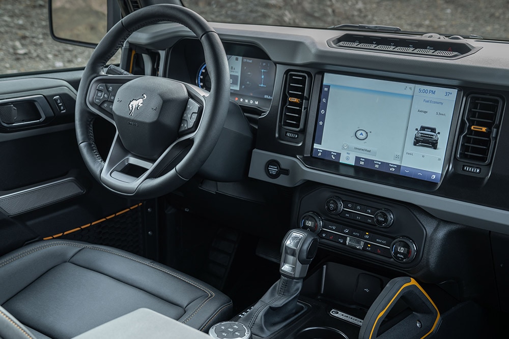 Vista degli interni di un Ford Bronco, con volante in pelle e touchpad integrato.