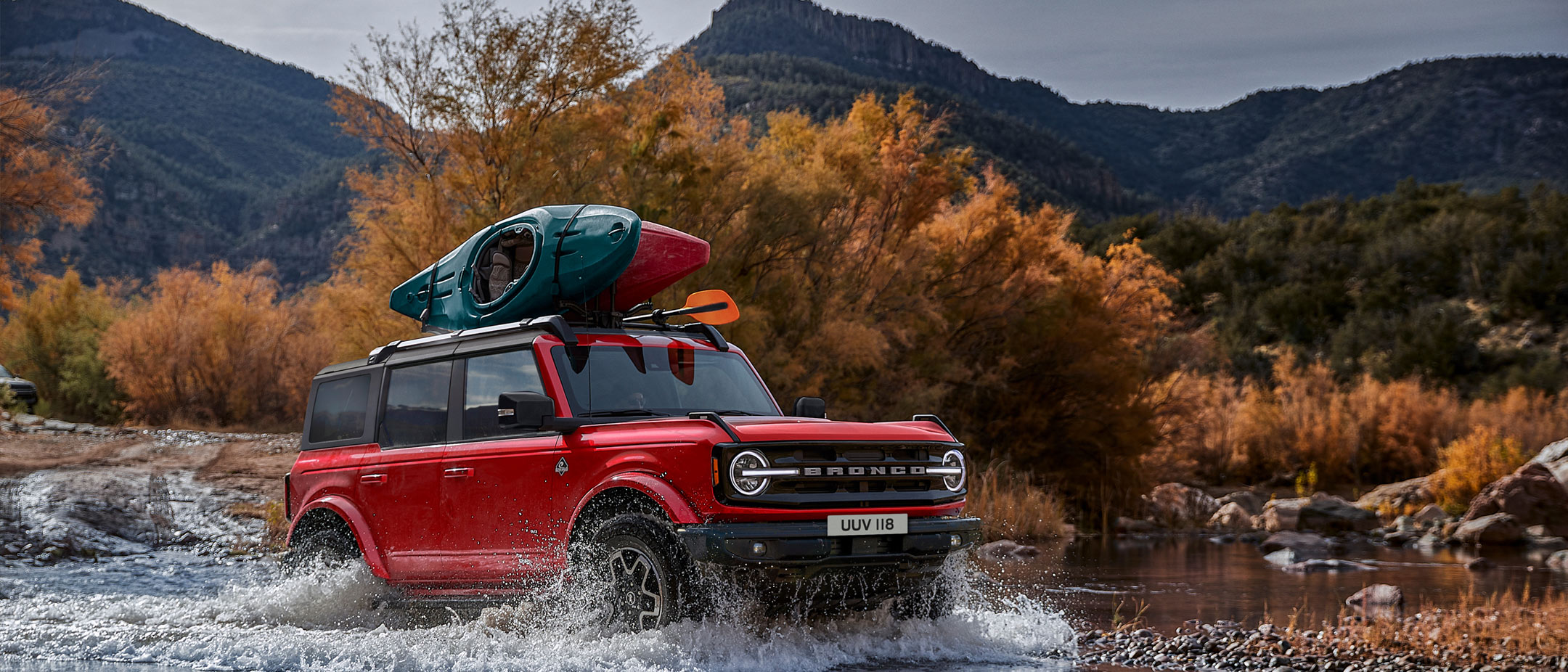 Ford Bronco grigio. Vista frontale a tre quarti, in marcia fuoristrada.