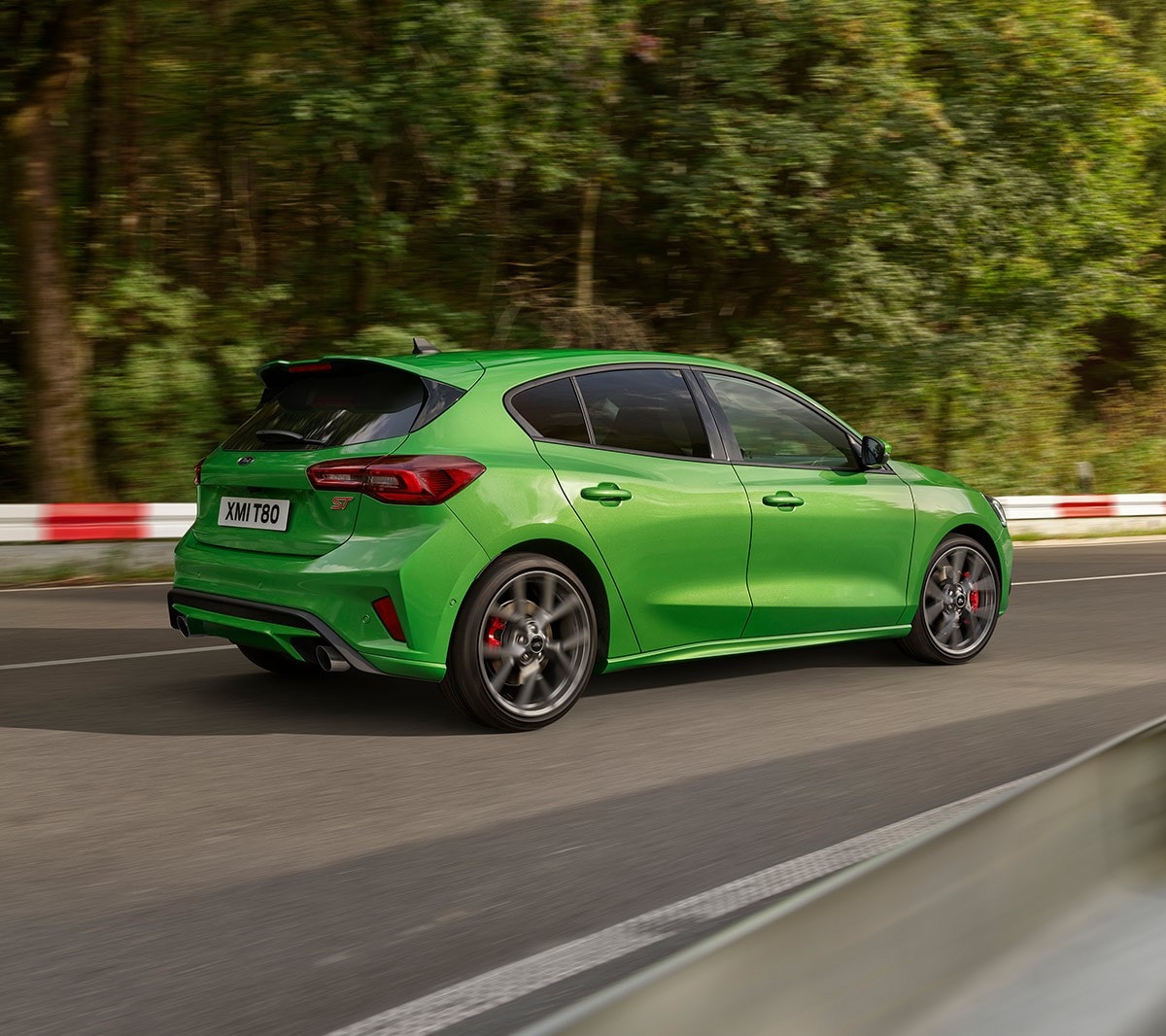 Ford Focus ST verde. Vista posteriore a tre quarti, in marcia su una strada.