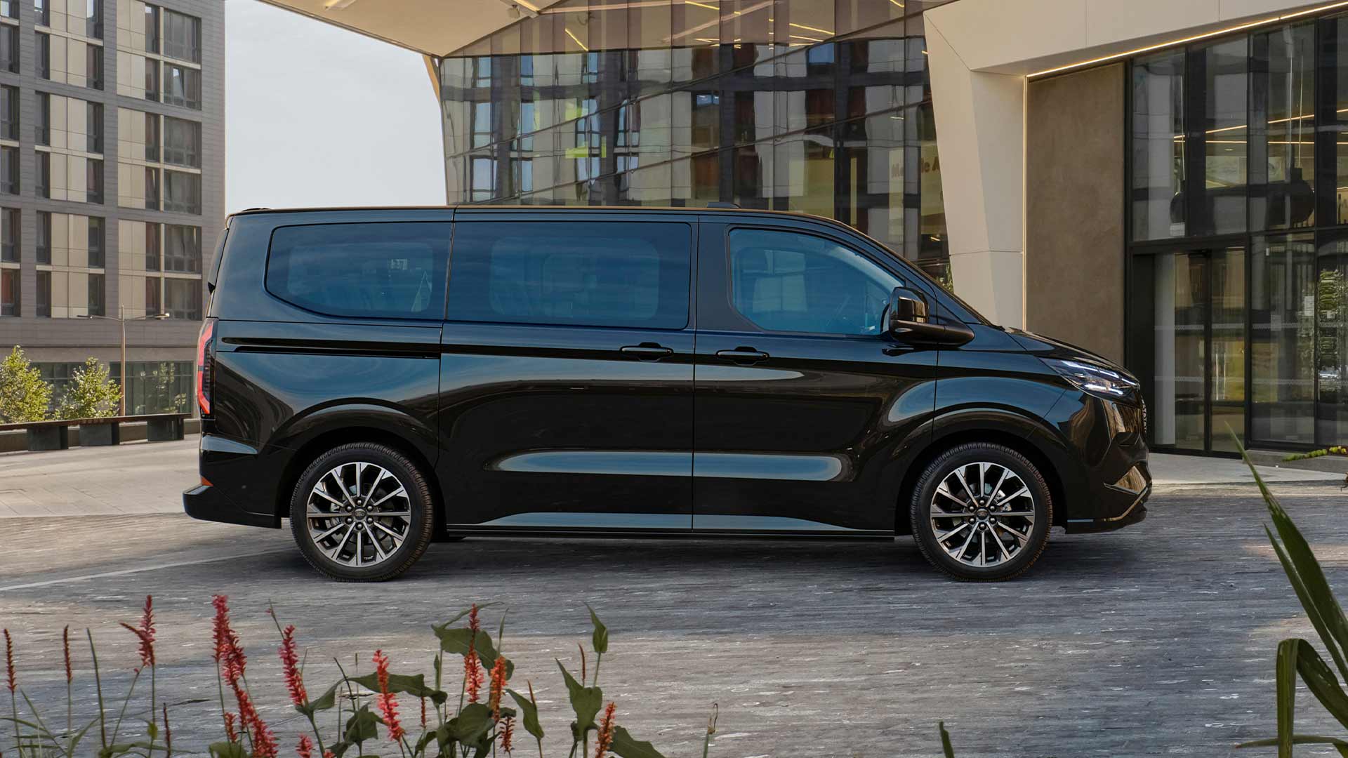 Ford E-Tourneo Custom nero parcheggiato davanti a un edificio moderno