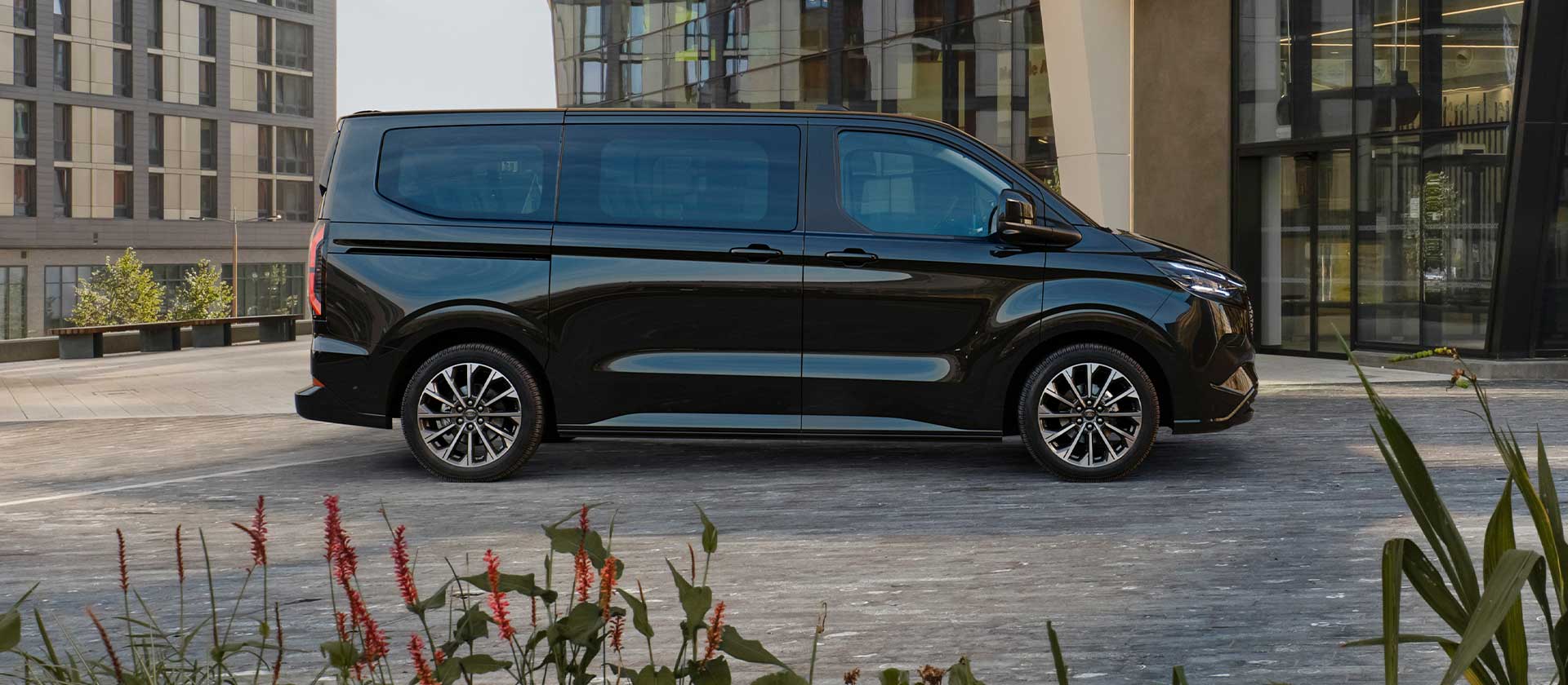 Ford E-Tourneo Custom nera parcheggiata davanti a un edificio moderno