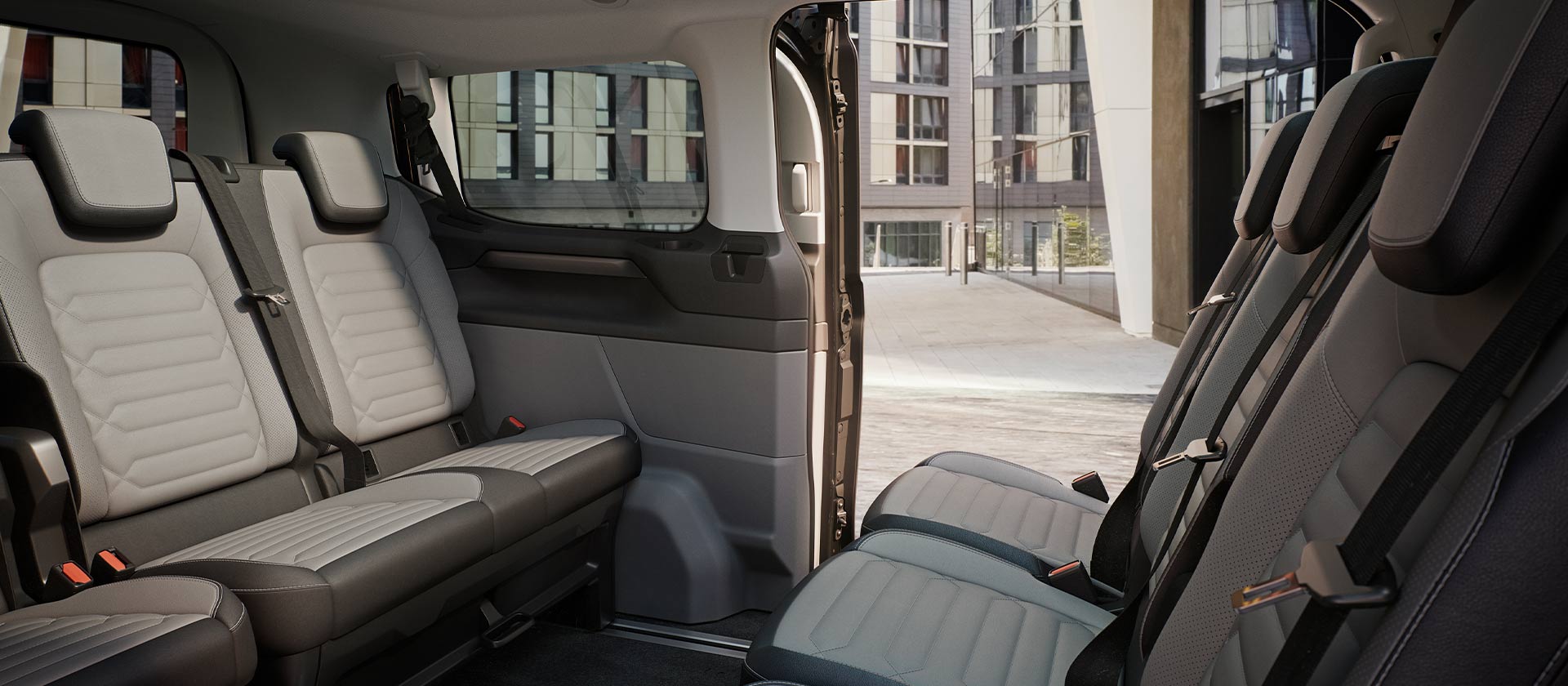 Interno della Ford Tourneo Custom con diverse file di sedili grigi e tetto panoramico