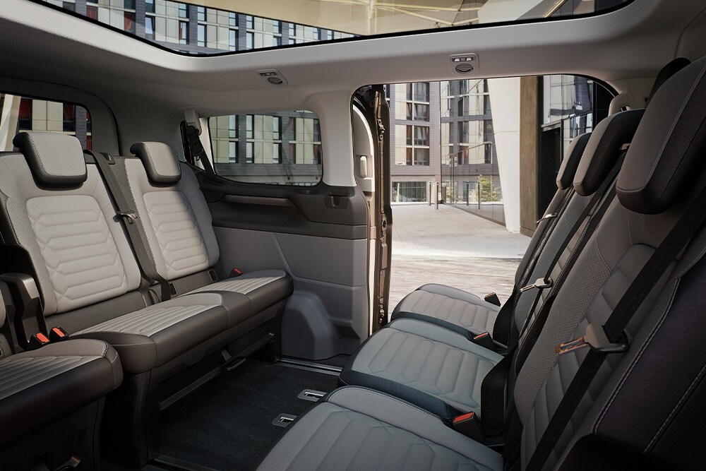 Interno della Ford Tourneo Custom con diverse file di sedili grigi e tetto panoramico
