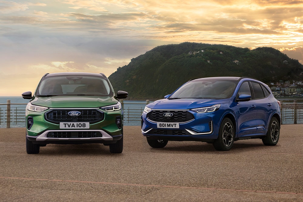 Una Ford Kuga Active verde e una Ford Kuga ST Line blu ferme fianco a fianco su un parcheggio lungo la costa. 