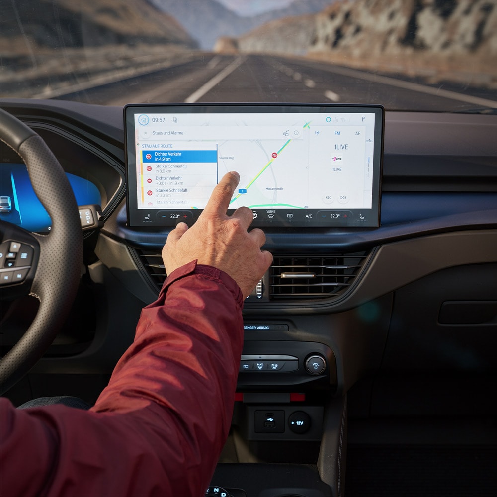 Un conducente utilizza la navigazione interconnessa sullo schermo digitale di una Ford Kuga BlueCruise Edition.