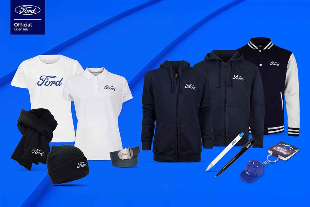 Collezione di merchandising Ford con vari veicoli Ford sullo sfondo, che include ombrello, tazze e capi d’abbigliamento a marchio Ford.