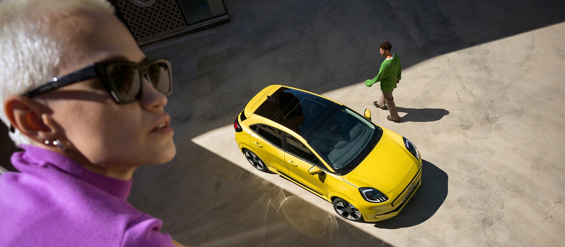 Vista aerea di una Ford Puma Gen-E® elettrica gialla. Persona in viola in primo piano.