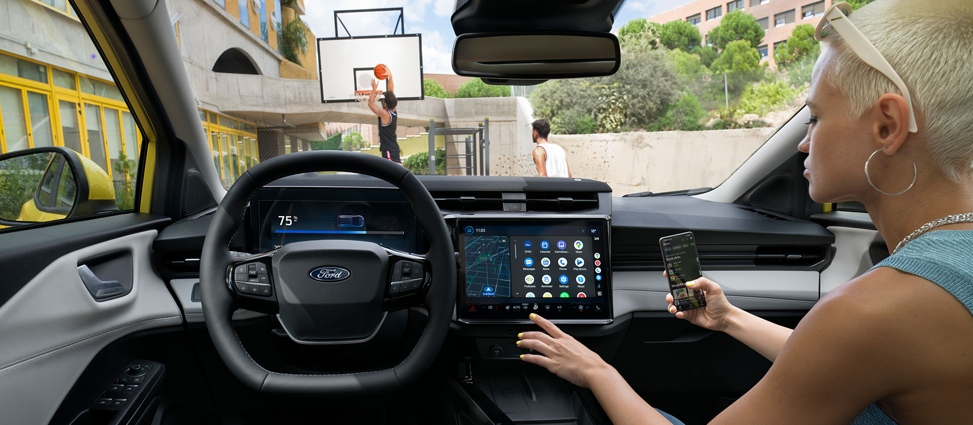 Interni della Ford Puma Gen-E® elettrica, con una donna che sincronizza in modalità wireless un cellulare con il touchscreen.