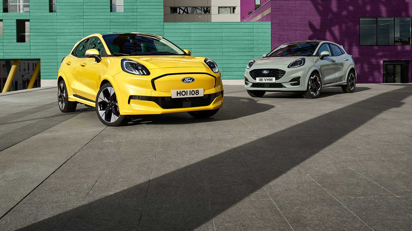 Una Ford Puma Gen-E® elettrica gialla parcheggiata accanto a una Ford Puma® benzina EcoBoost® grigia. 