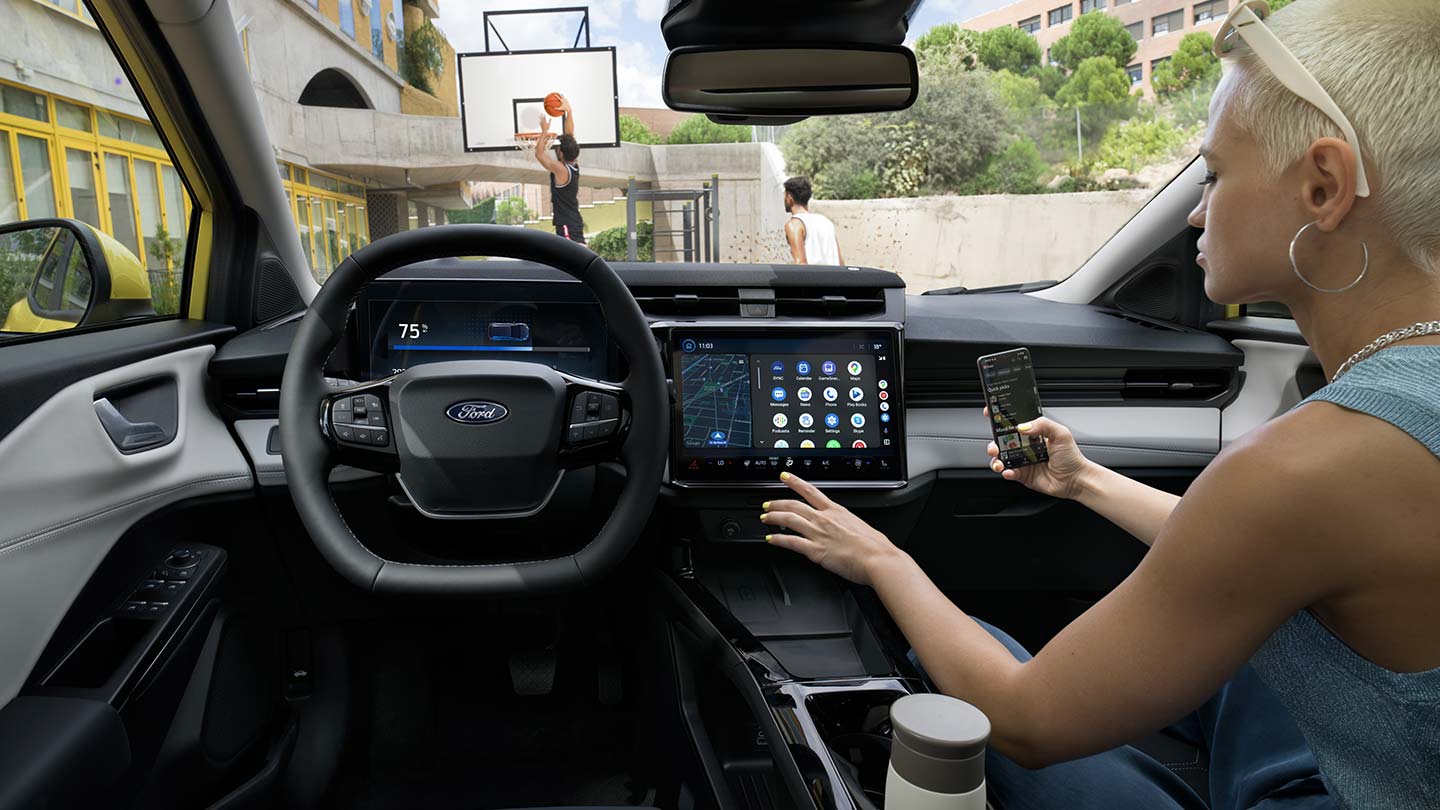 Interni della Ford Puma Gen-E® elettrica, con una donna che sincronizza in modalità wireless un cellulare con il touchscreen.