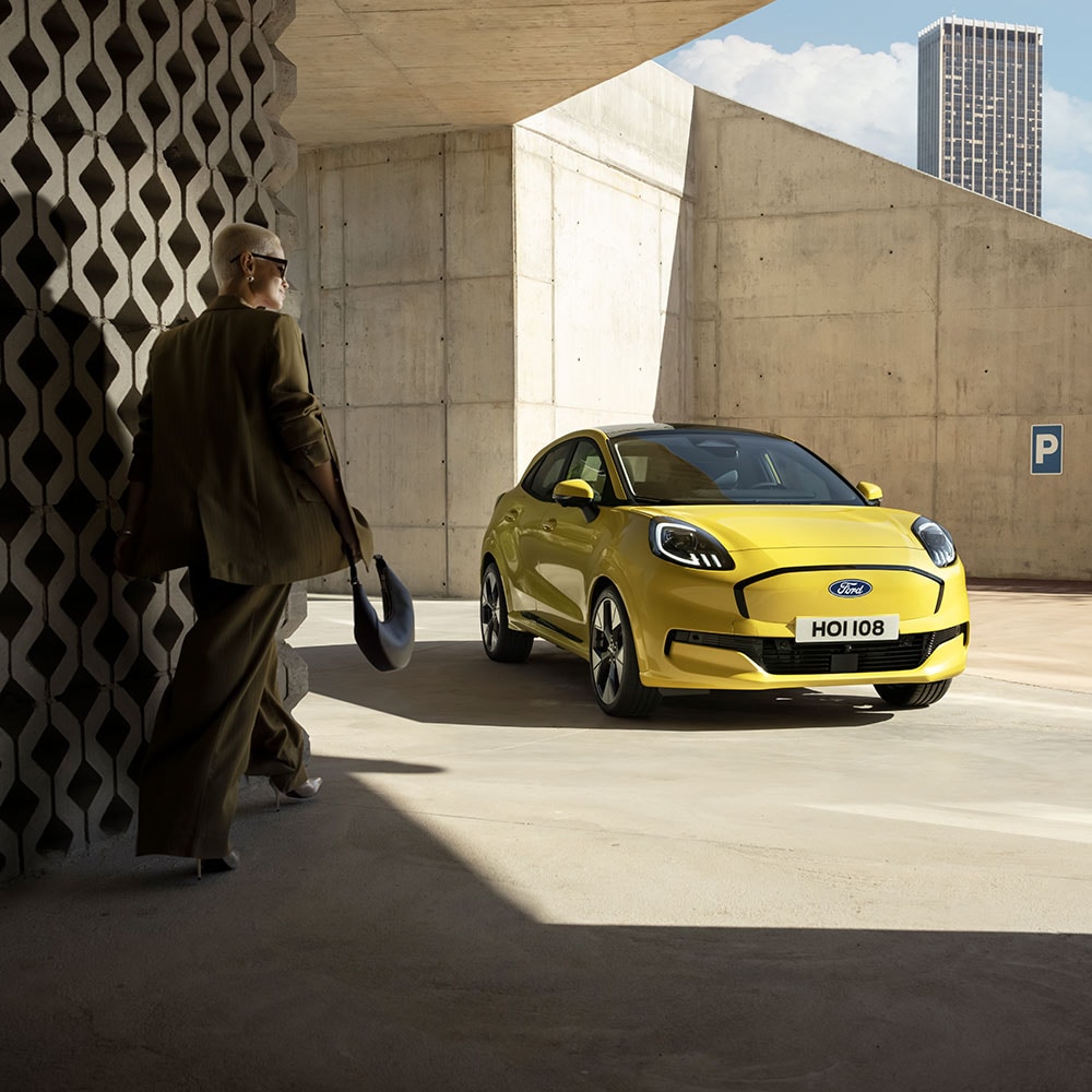 Una persona cammina verso la nuova Ford Puma Gen-E® elettrica gialla.