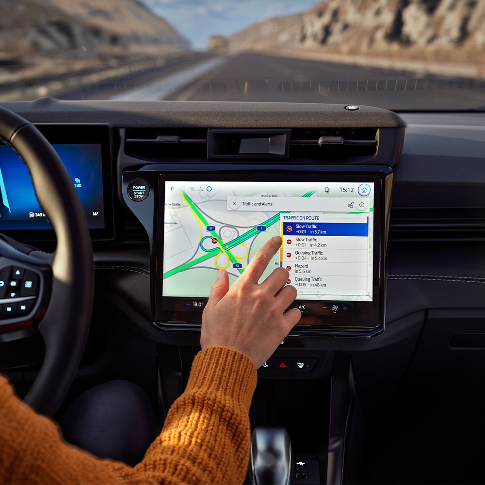 Un conducente utilizza la navigazione interconnessa sullo schermo digitale di una Ford Puma BlueCruise Edition.