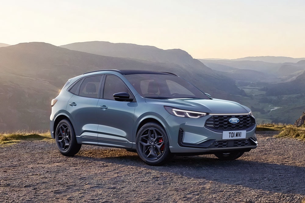 Una Ford Kuga grigia parcheggiata al tramonto su una strada sterrata.