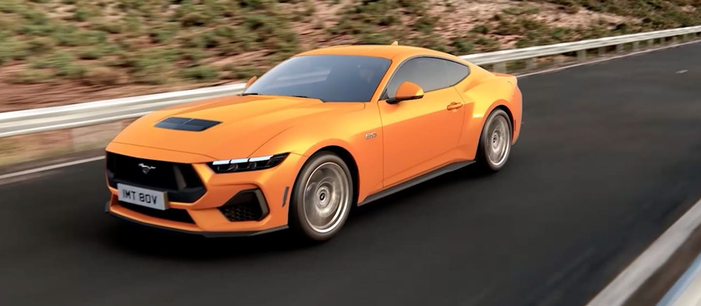 Ford Mustang GT Fastback in vernice Orange Fury che percorre una strada di montagna