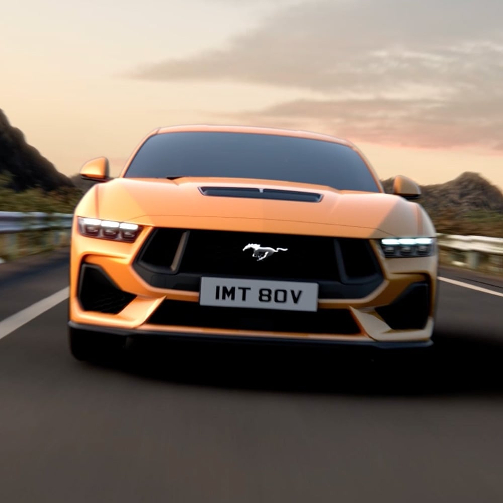 Vista frontale di una Ford Mustang arancione con primo piano dei fari, della griglia e del badge Mustang
