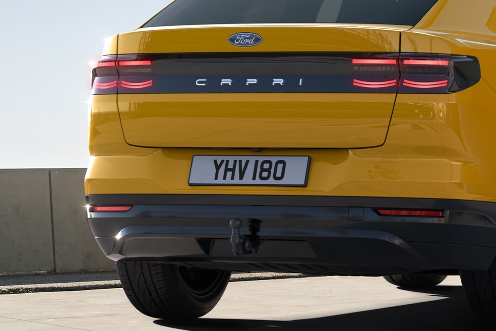 Vista posteriore di una Ford Capri® gialla che guida su una strada cittadina.