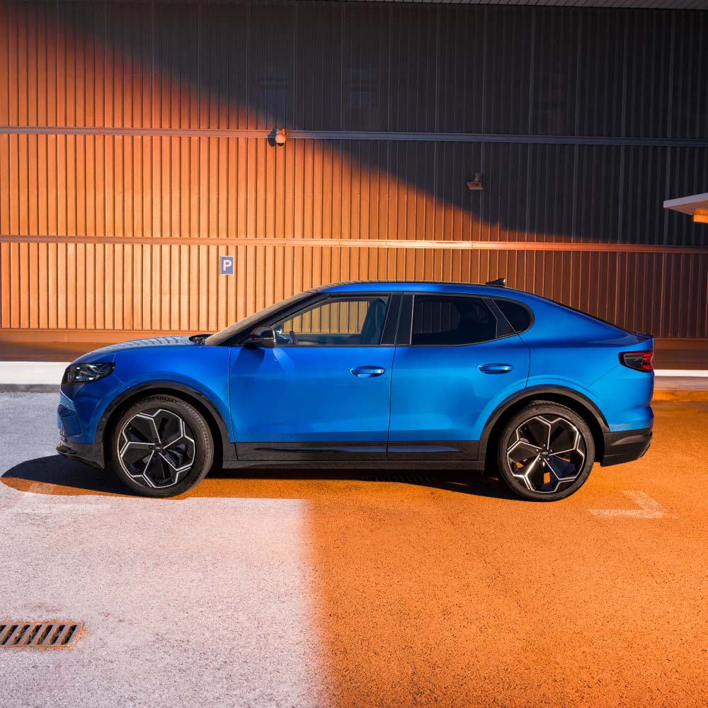 Vista laterale di una Ford Capri blu parcheggiata davanti a un muro strutturato.