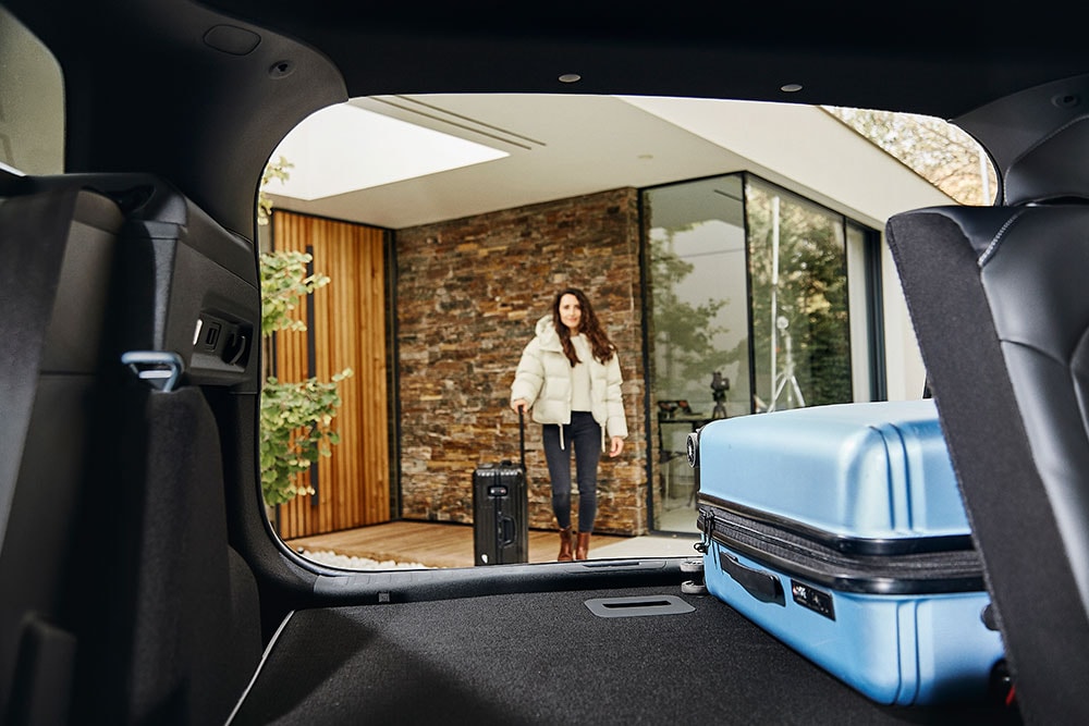 Il bagagliaio posteriore del Ford Explorer, visto dall’interno dell’auto, con una valigia blu.