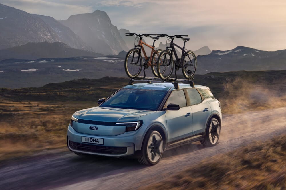 Ford Explorer blu su strada sterrata, con barre trasversali, portabici da tetto con due biciclette alloggiate.