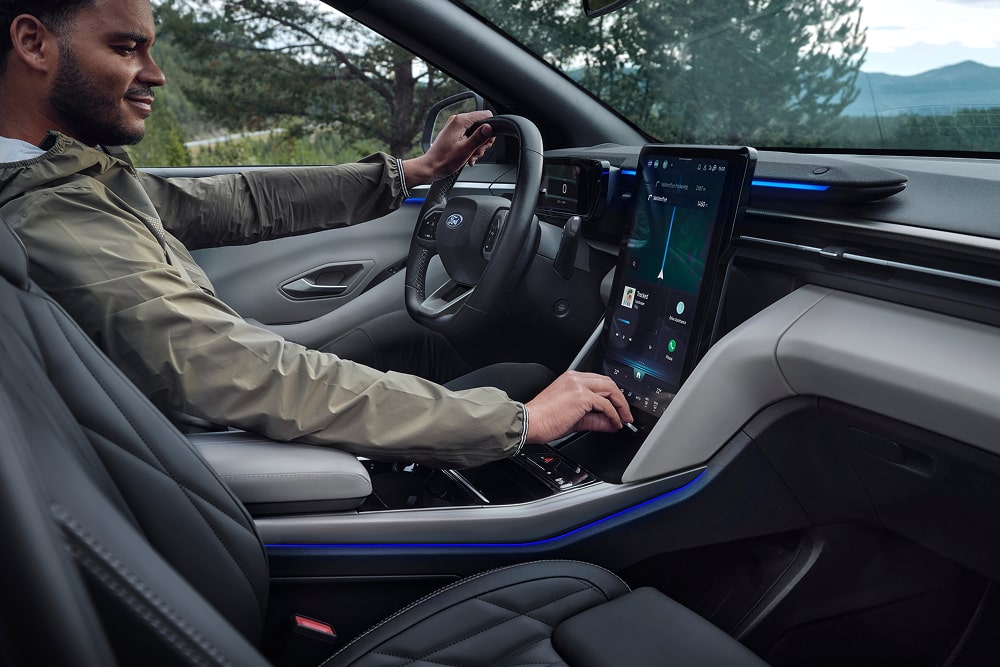 Guidatore che usa il sistema infotainment su touchscreen all’interno di un SUV familiare Ford Explorer.