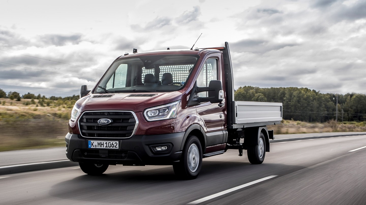 Ford Transit Chassis Cab rosso, vista frontale a tre quarti, in transito su una strada extraurbana