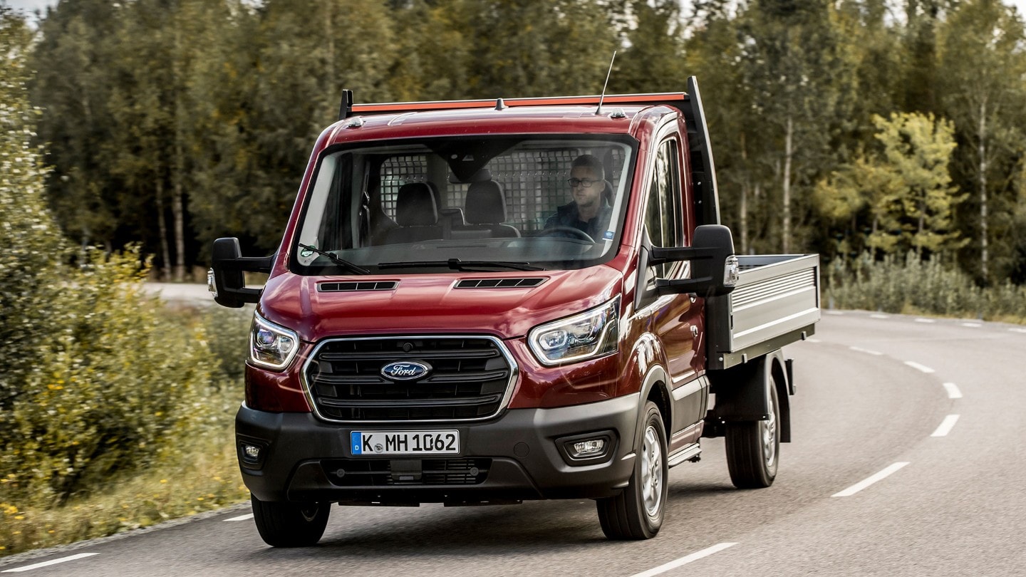 Ford Transit Chassis Cab rosso, vista frontale a tre quarti, in marcia su una strada extraurbana