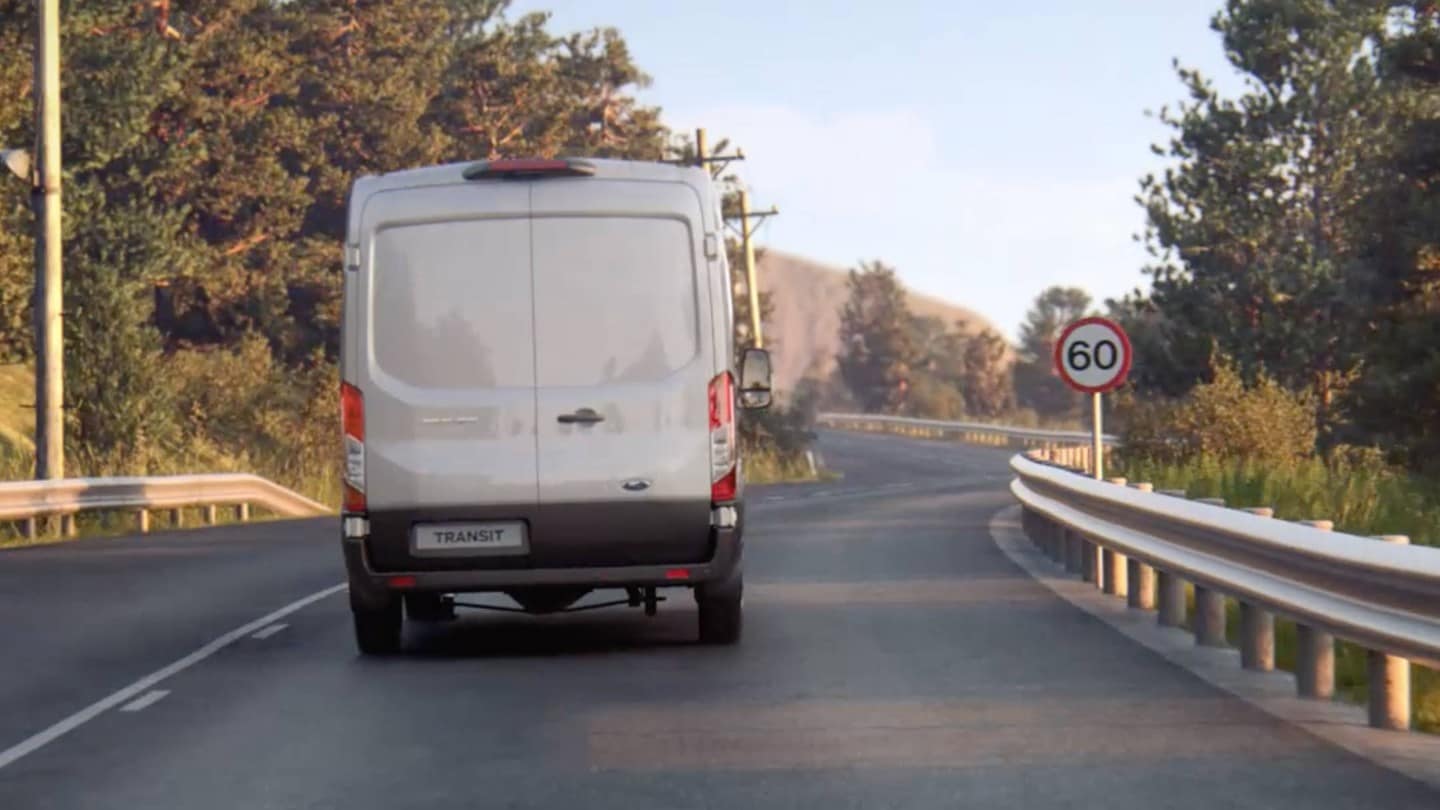 Ford Transit Van in marcia su strada con cartello, vista posteriore