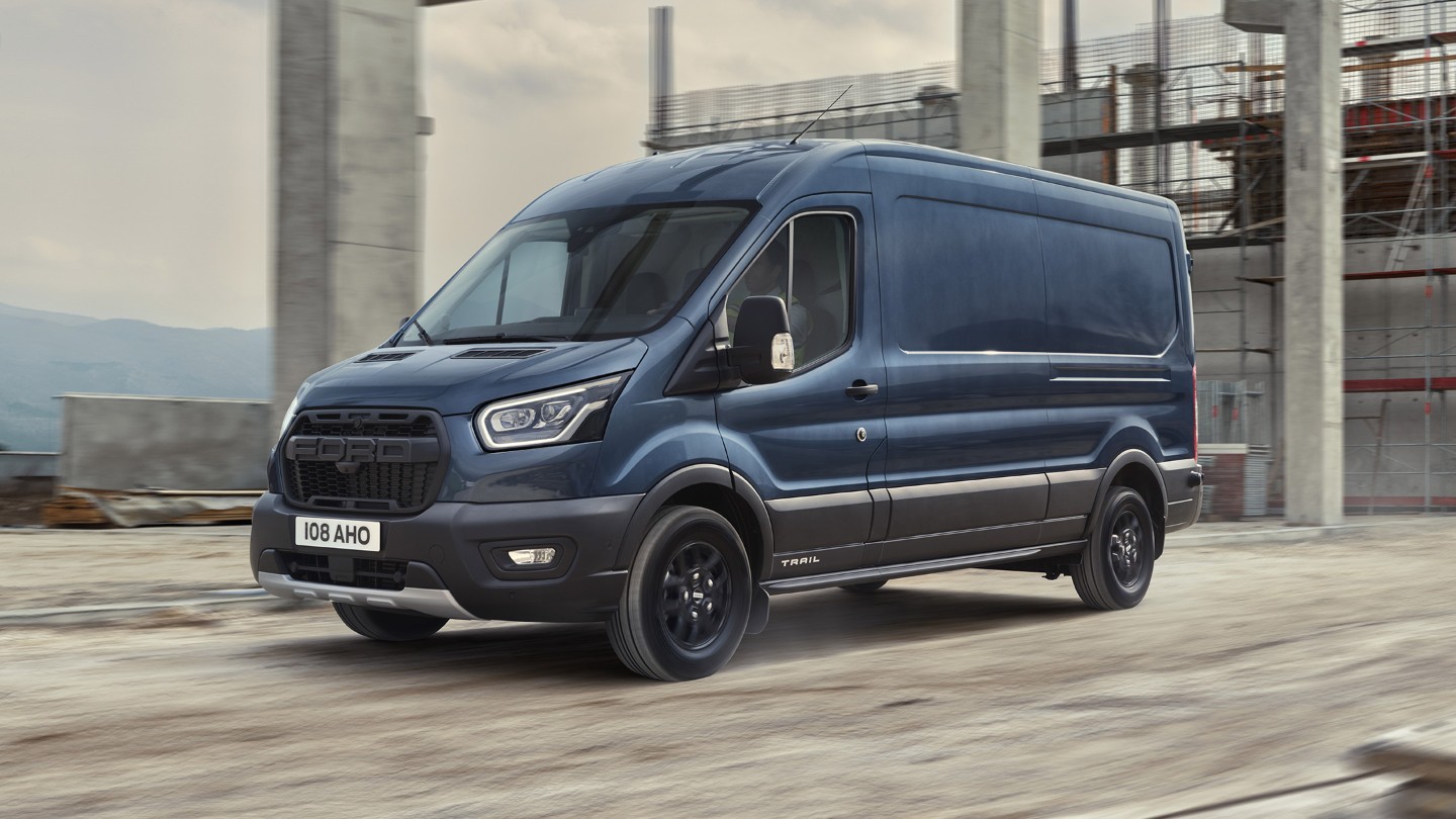 Ford Transit Trail furgone cabinato blu, vista laterale a tre quarti, in movimento sull’area di un cantiere 