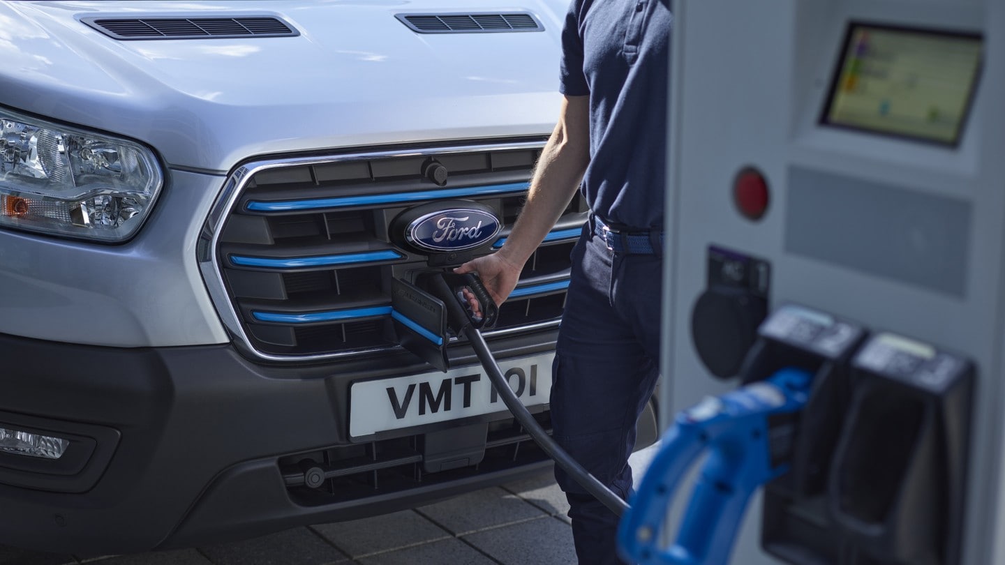 Ford E-Transit bianco, vista frontale a tre quarti con dettaglio della calandra, in fase di carica