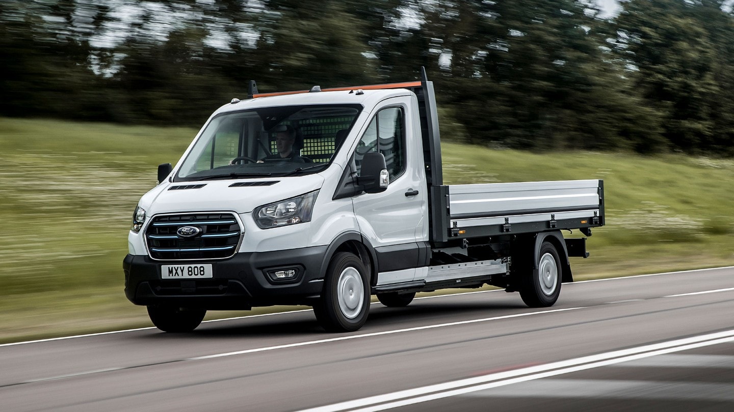 Ford E-Transit Chassis Cab bianco, vista frontale a tre quarti, in marcia su una strada extraurbana 