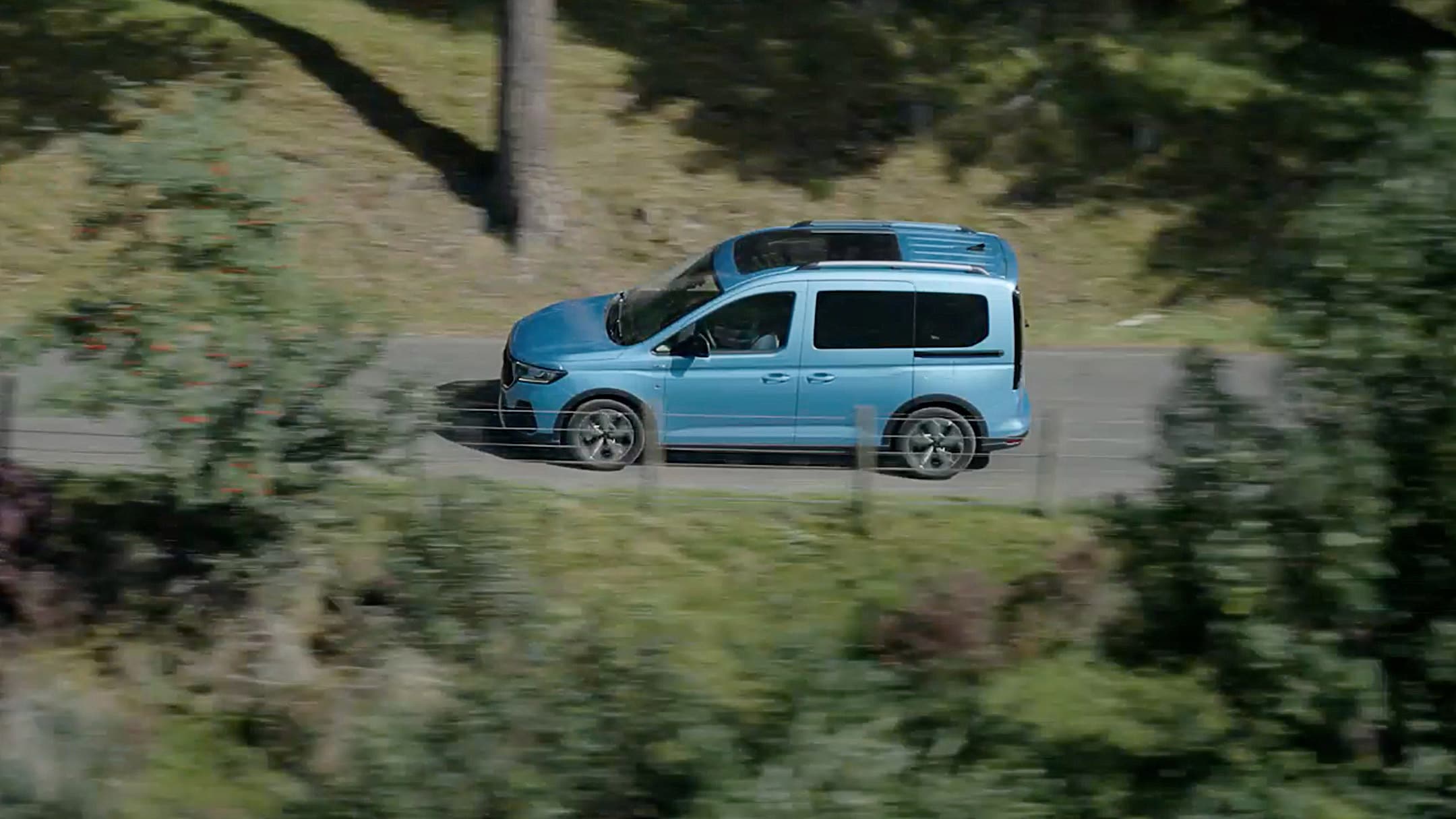 Ford Tourneo Connect azzurro, vista laterale dall’alto, in transito su una strada extraurbana