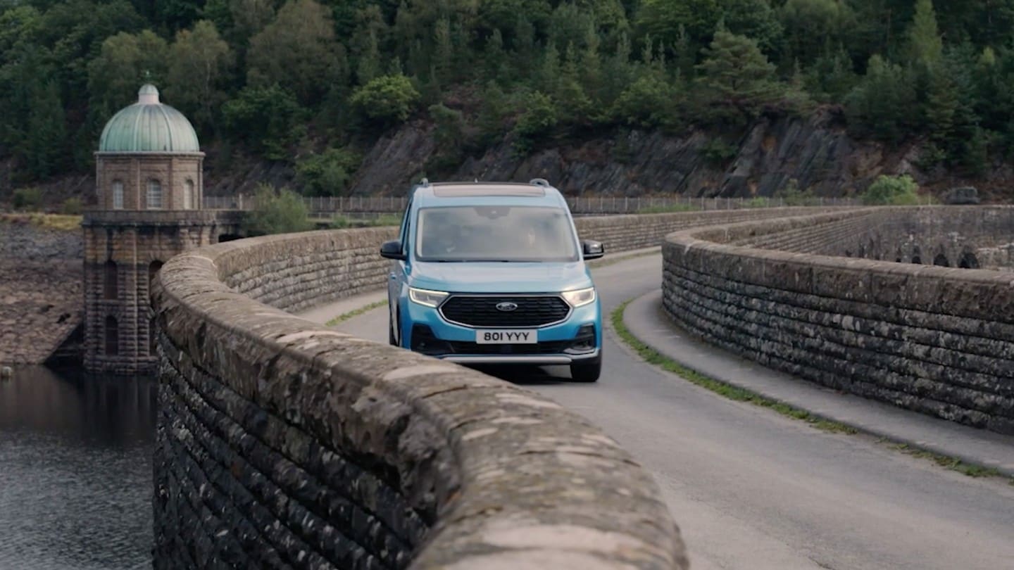 Ford Tourneo Connect azzurro, vista frontale, in transito su un ponte di pietra tortuoso