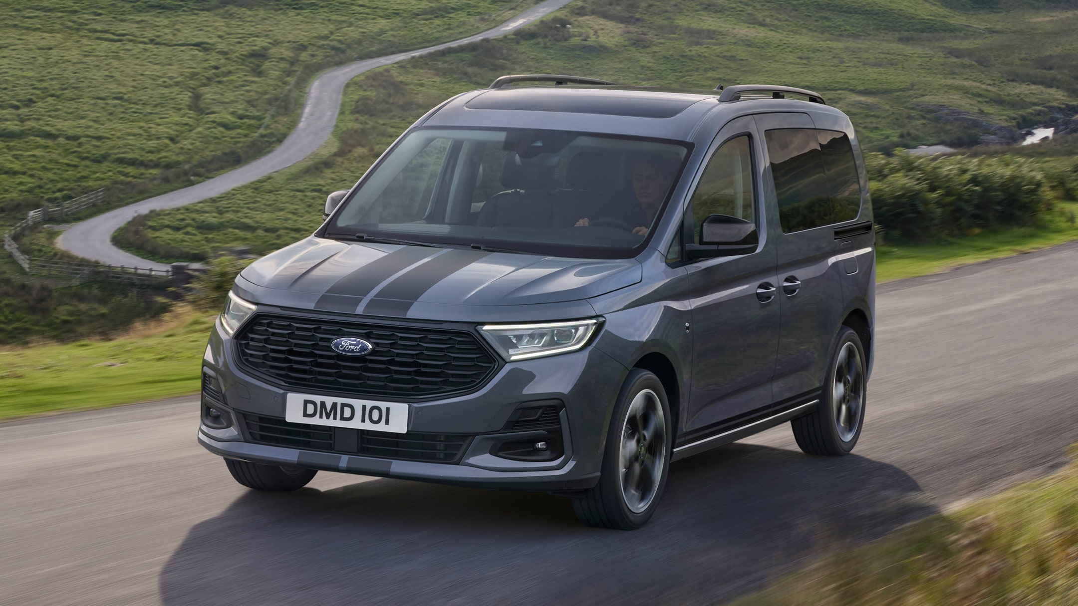 Ford Tourneo Connect grigio, vista frontale a tre quarti, in transito su una strada di montagna con fiume sullo sfondo