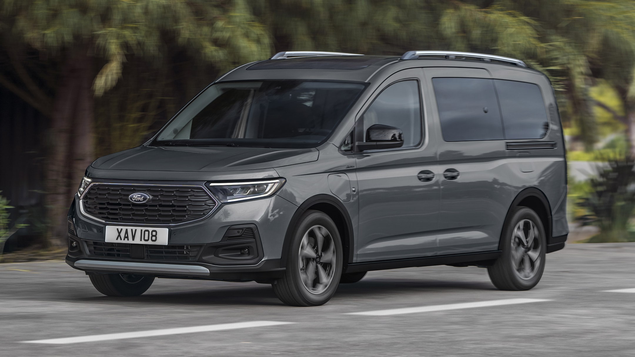 Ford Tourneo Connect grigio, vista frontale a tre quarti, in transito su una strada di montagna con fiume sullo sfondo