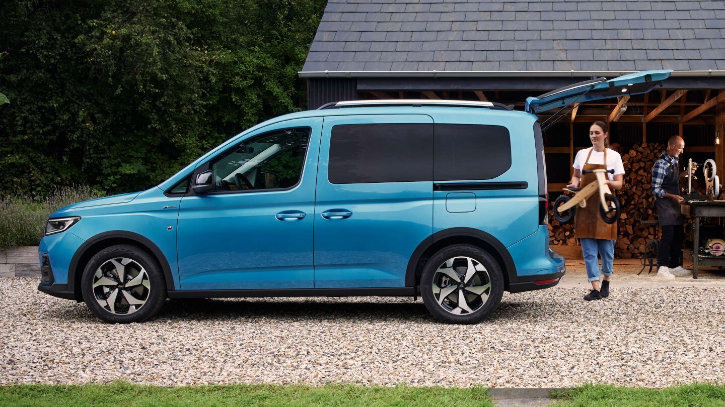 Ford Tourneo Connect azzurro, vista laterale con portellone posteriore aperto, una donna carica il bagagliaio