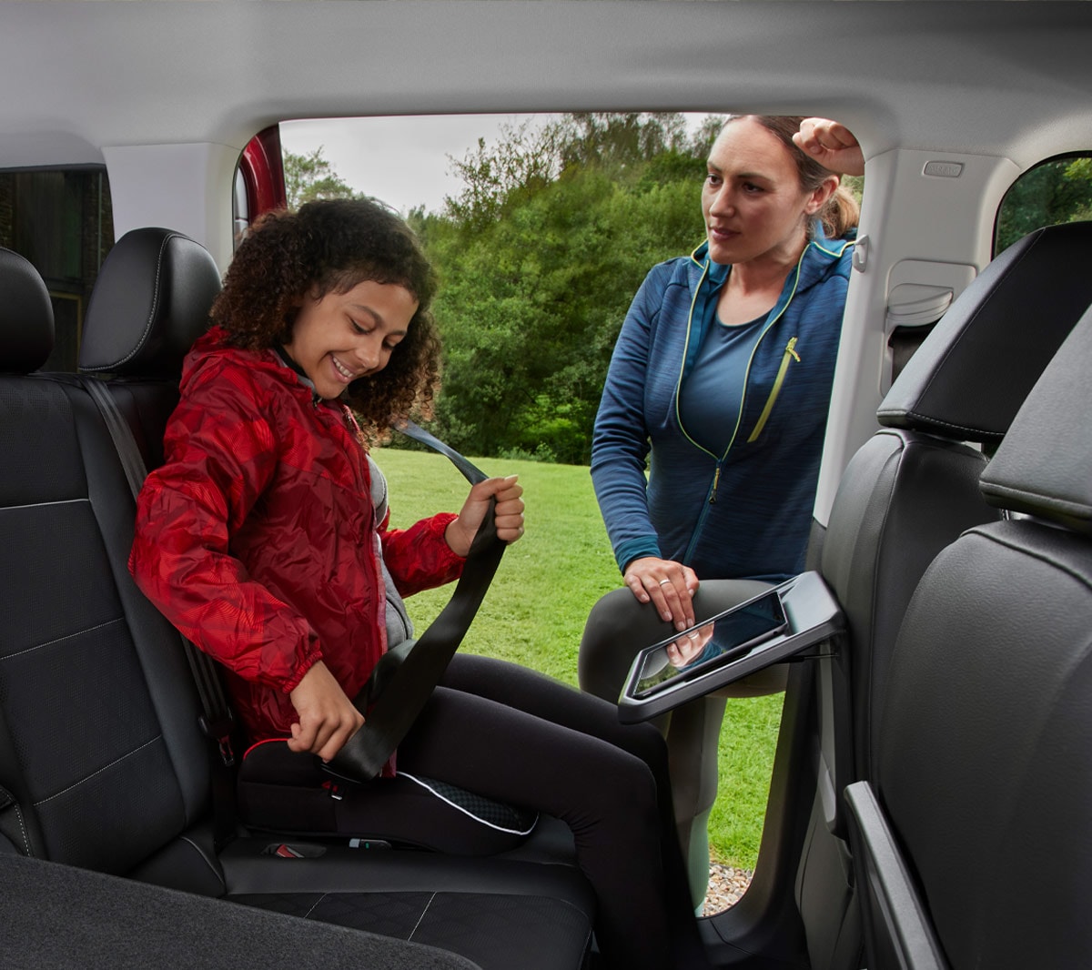 Ford Tourneo Connect, abitacolo, vista della seconda e terza fila di sedili, una ragazza si allaccia la cintura di sicurezza