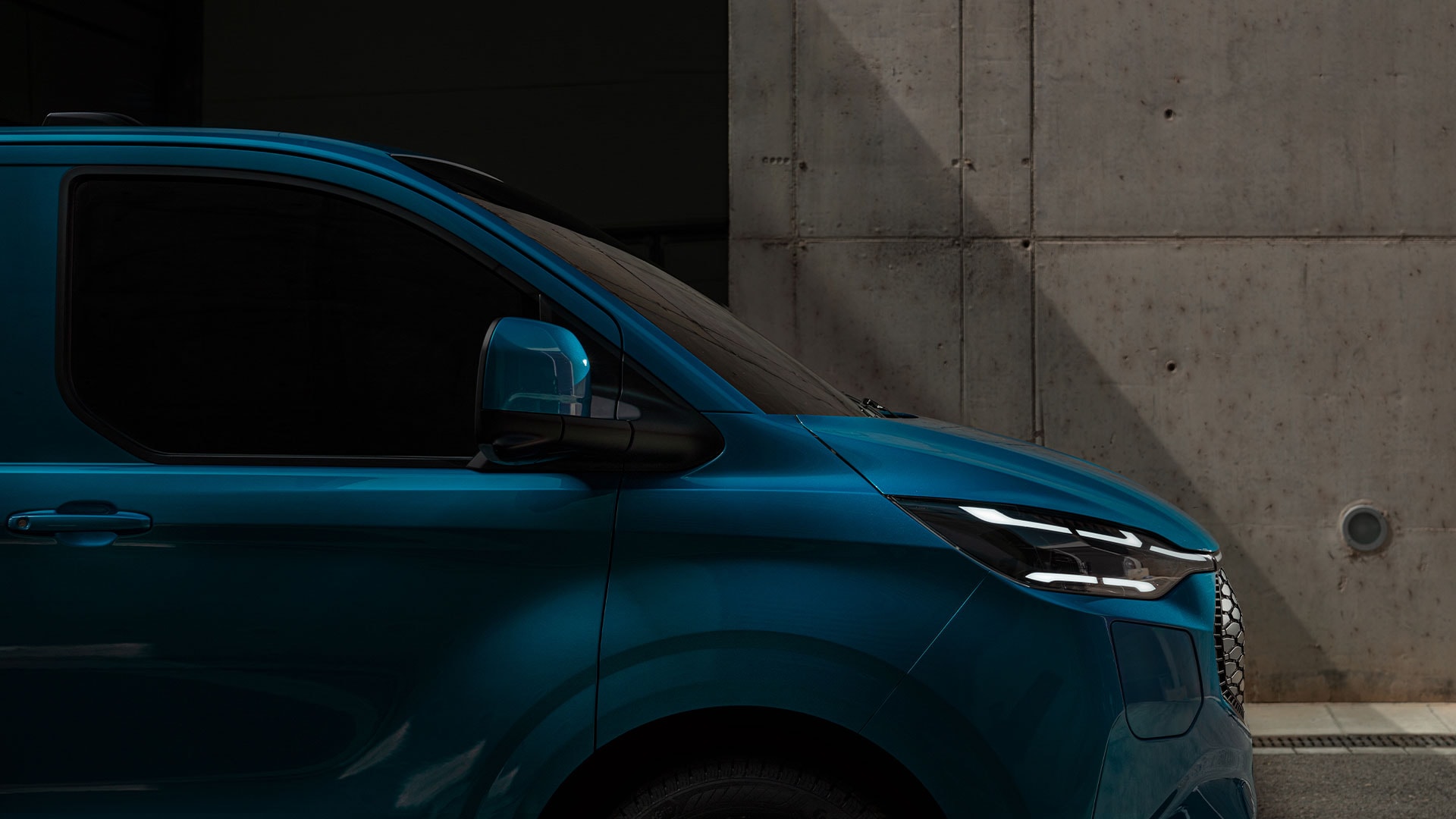 Primo piano del faro a LED di un Ford E-Transit Custom blu.
