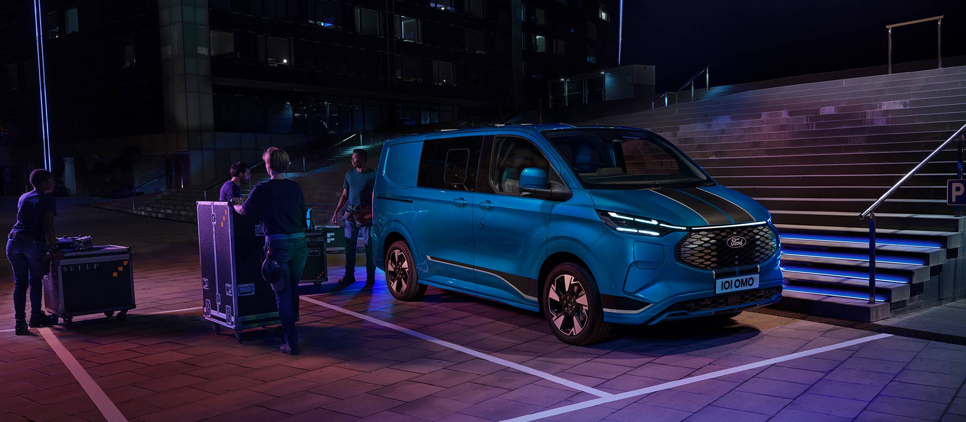 Un furgone elettrico Ford E-Transit Custom blu viene caricato durante la notte.