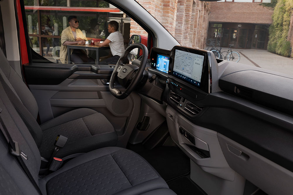 Person sitting in the driver's seat of a red Ford Transit Custom.