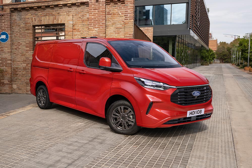 Delivery person unloading packages from a red Ford Transit Custom.