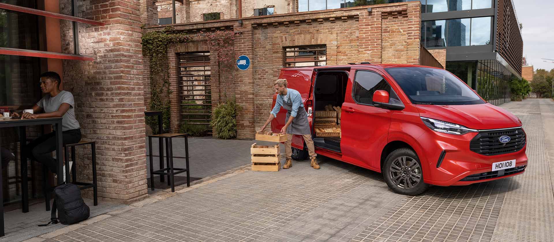 Furgone Ford Transit Custom rosso parcheggiato davanti a un caffè.