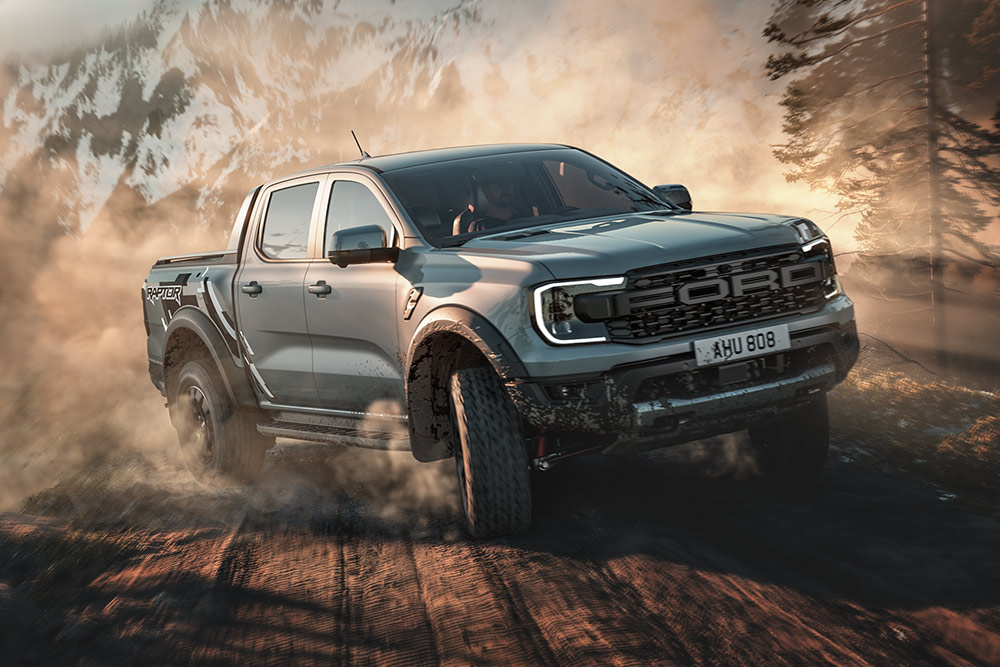 Ford Ranger Raptor che percorre una strada sterrata in modalità Baja, con un paesaggio montano sullo sfondo.