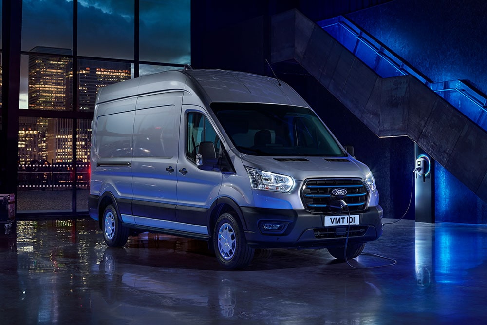 Furgone Ford E-Transit parcheggiato vicino a un punto di ricarica in un deposito.