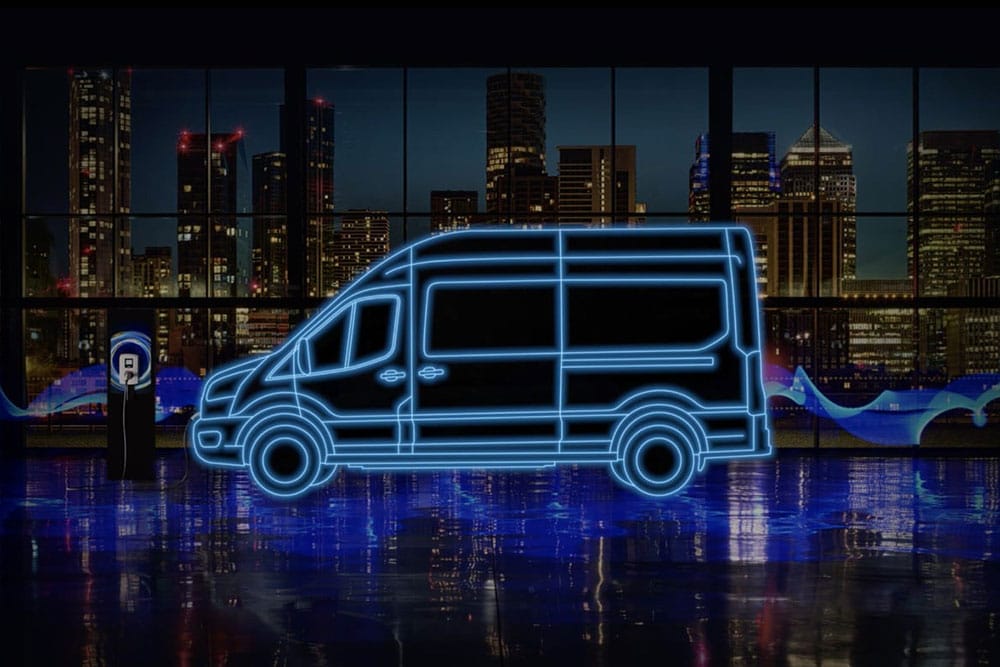 Sagoma blu fluo di un furgone elettrico Ford E-Transit e di una stazione di ricarica sul profilo della città.
