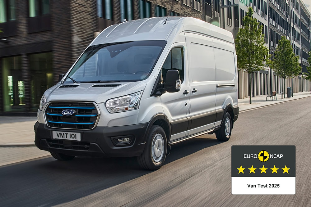 Furgone elettrico Ford E-Transit  di colore argento che percorre una strada con distintivo "Gold 2022 Commercial Van Safety".
