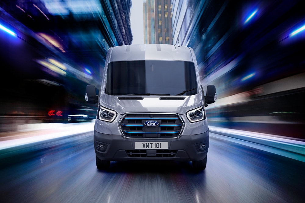 Furgone elettrico Ford E-Transit grigio scuro che percorre una strada.