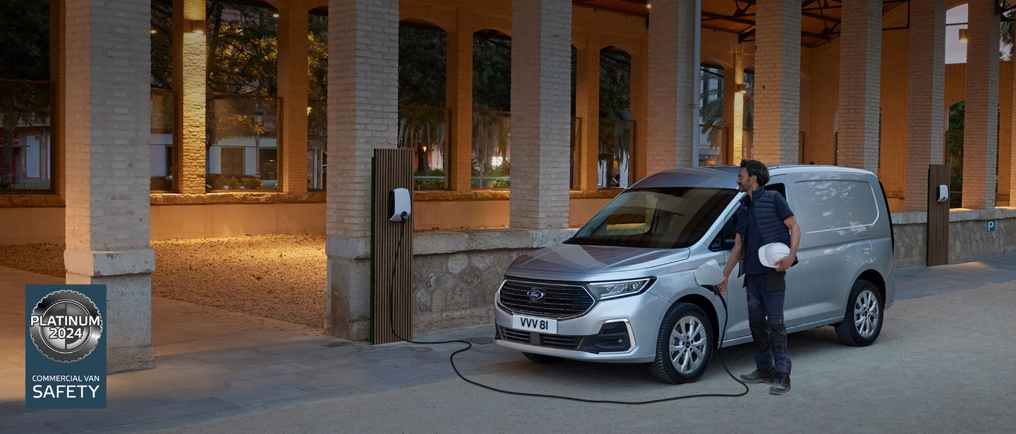 Un uomo con indosso un casco collega il cavo di una Wallbox a un Ford Transit Connect color Stardust Silver.