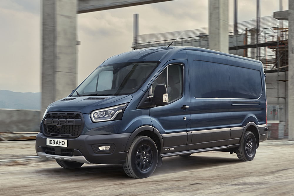 Ford Transit Trail furgone cabinato blu, vista laterale a tre quarti, in movimento sull’area di un cantiere