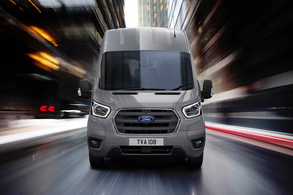 Vista frontale di un furgone Ford Transit che attraversa la città.